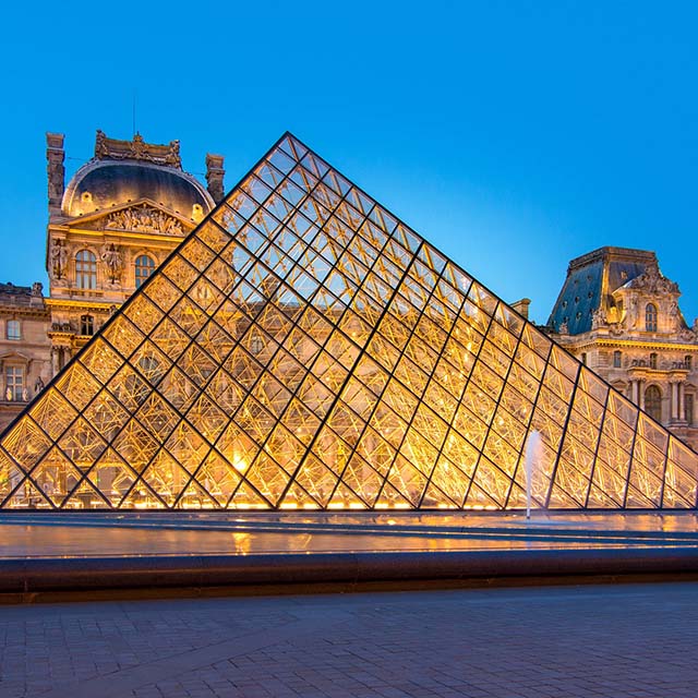 Louvre Museum in Paris, featuring the iconic glass pyramid illuminated at night