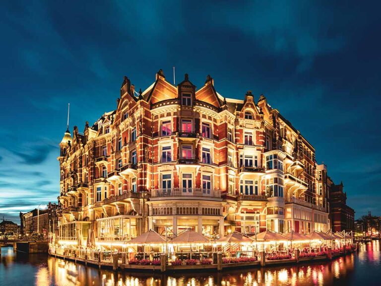 Exterior of De L'Europe Amsterdam illuminated at night with elegant lighting along the canals